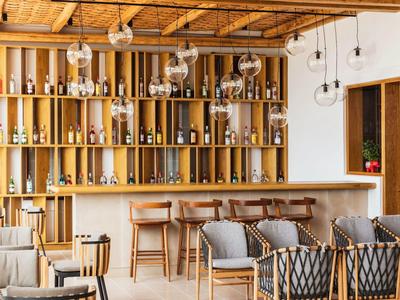 Bar di hotel moderno con scaffali in legno, sedie e divani in un'atmosfera calda e accogliente.