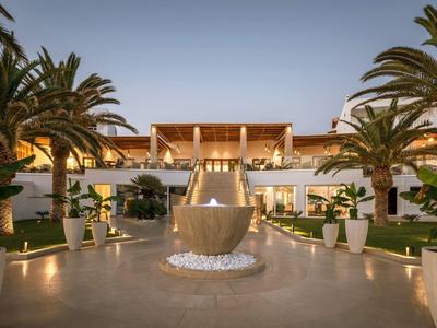 Elegante edificio dell'hotel con fontana illuminata e piante tropicali.