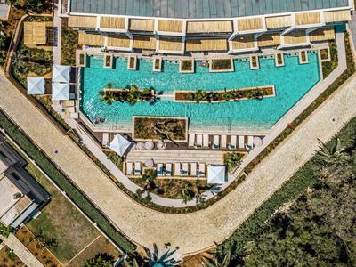 Vista aerea di una grande piscina triangolare con lettini e vegetazione intorno.