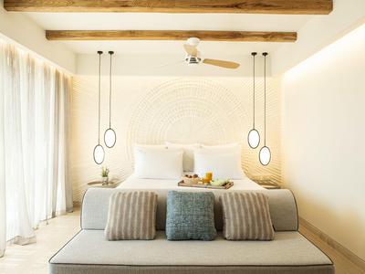 Camera luminosa con letto matrimoniale, ventilatore a soffitto e due lampade sospese in una stanza d'albergo.