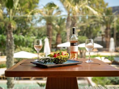 Un tavolo in legno apparecchiato con una bottiglia di vino, due bicchieri e un piatto di salumi e olive.