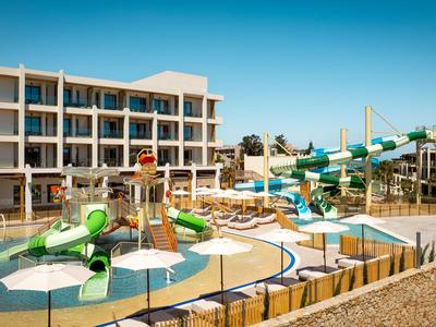 Meerdere verdiepingen tellend hotel met waterpark en glijbanen onder heldere zonnige lucht.