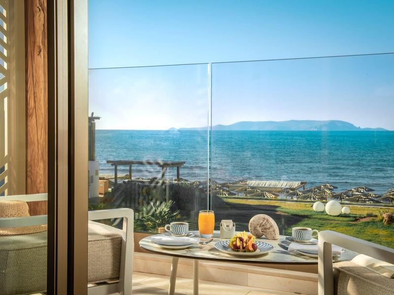 Un tavolo per la colazione apparecchiato su una terrazza con vista mare e cielo sereno.