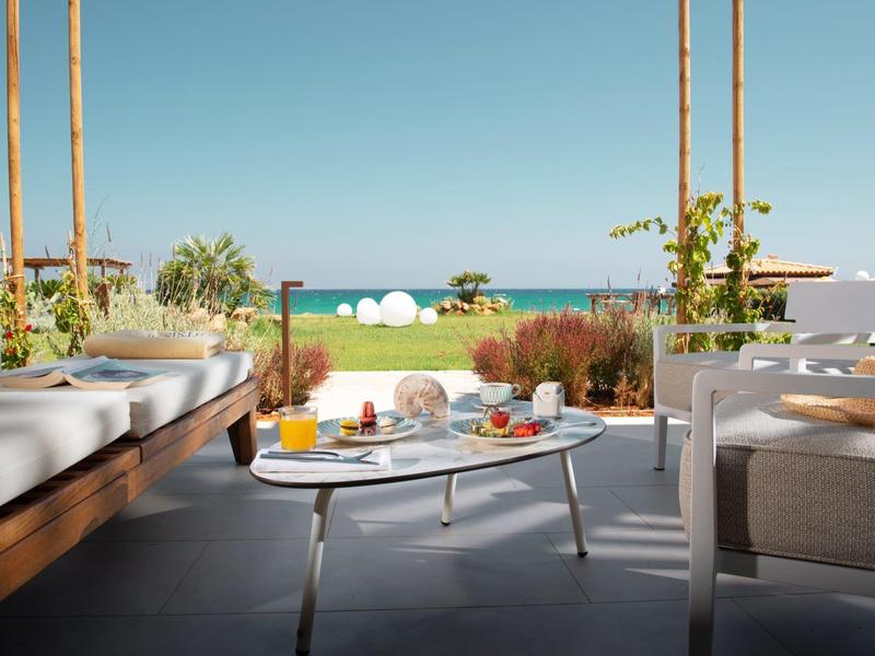 Terrazza con zona salotto moderna e tavolo per colazione con vista sul mare sullo sfondo.