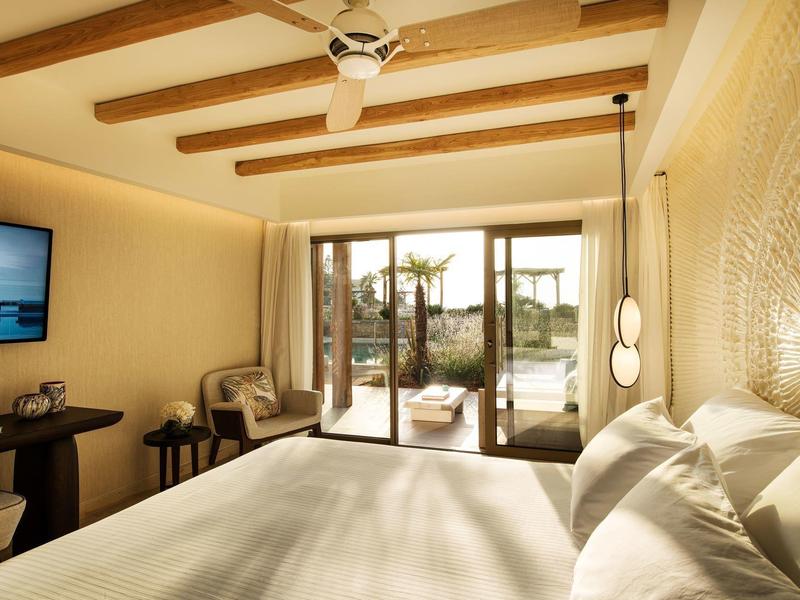 Camera d'hotel luminosa con soffitto con travi in legno e vista su terrazza e giardino