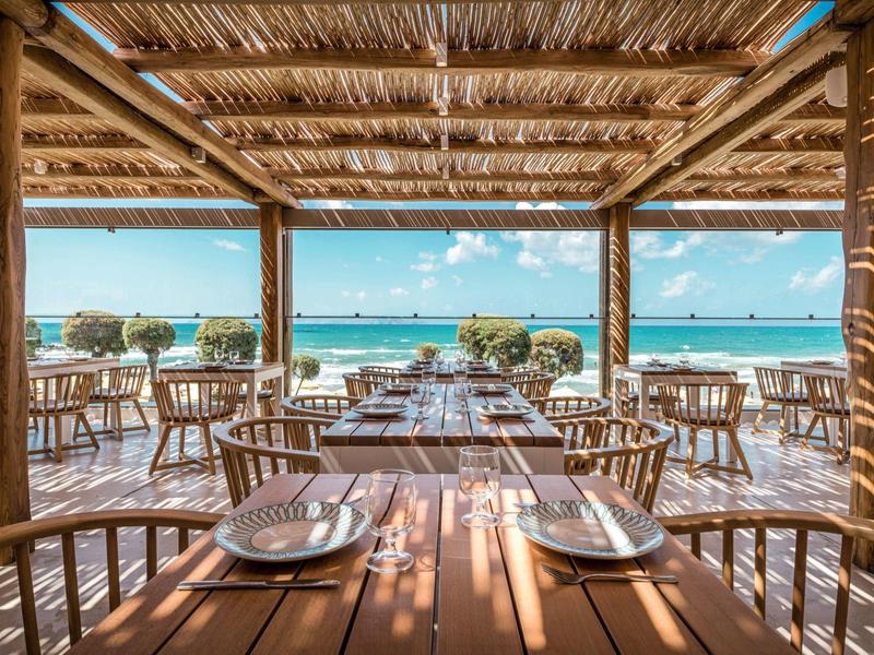Ristorante aperto con mobili in legno con vista sul mare sotto un cielo limpido.