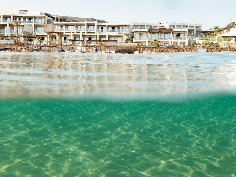 Edificio di hotel moderno sulla riva con acqua limpida in primo piano.
