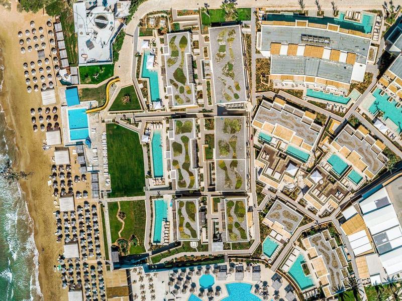 Vista aerea di un resort con piscine, edifici e il mare adiacente