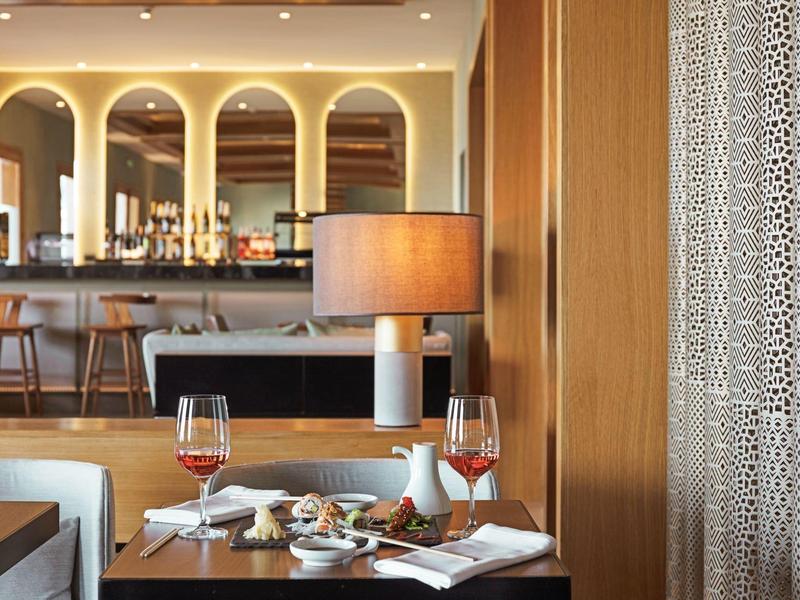 Un accogliente zona ristorante con tavolo apparecchiato, bicchieri di vino e un bar sullo sfondo.