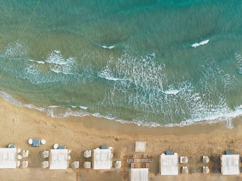 Spiaggia con lettini e ombrelloni lungo la riva di un mare mosso.