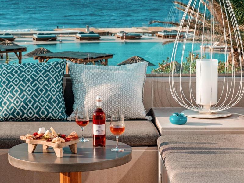 Lounge accogliente con cuscini, vino e snack sulla costa con vista sul mare.