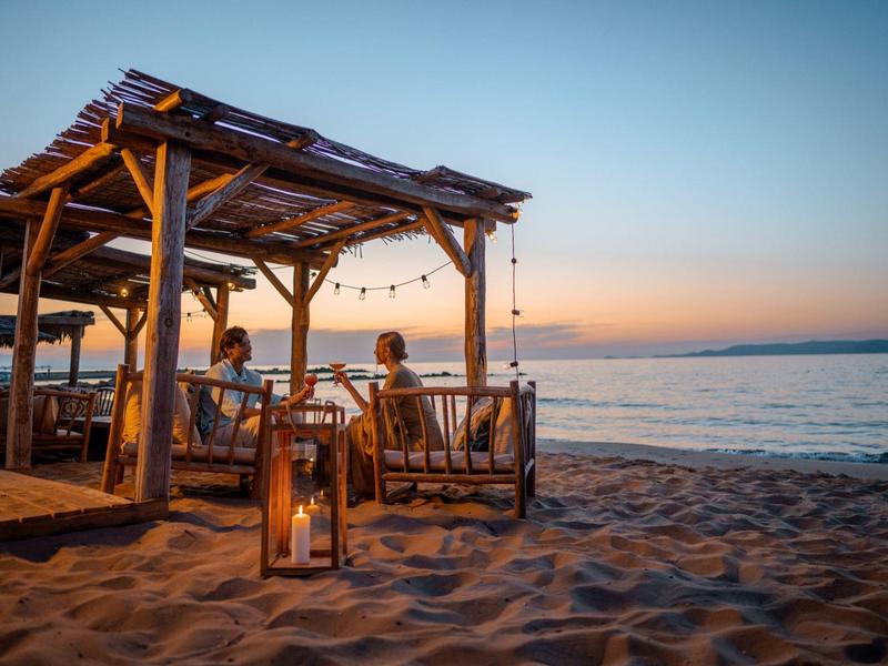 Capanna sulla spiaggia con posti a sedere e lanterne al tramonto vicino al mare