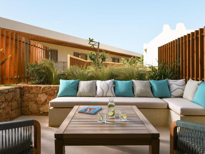 Accogliente terrazza con area salotto, cuscini e tavolo con bevande e riviste.