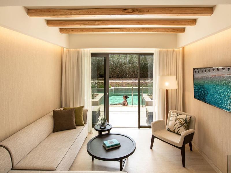 Soggiorno moderno con divano, poltrona, tavolino e vista sulla piscina.