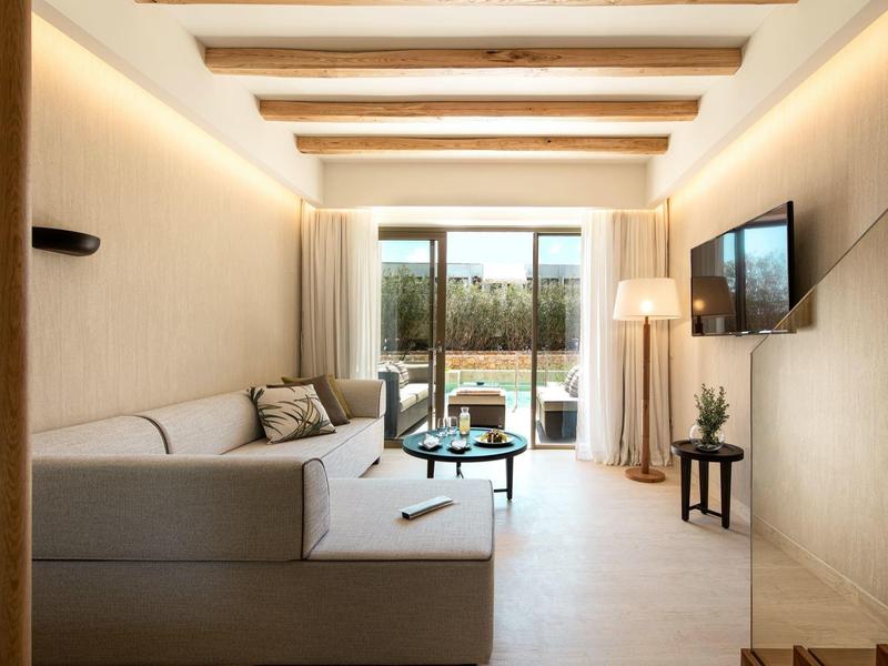 Soggiorno moderno con pareti chiare, angolo divano e balcone sullo sfondo.