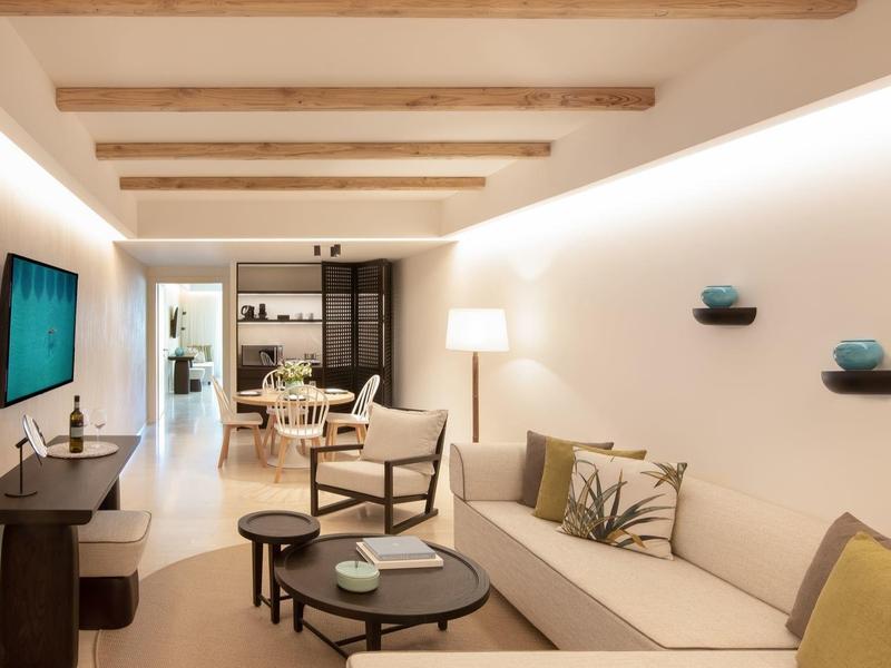 Soggiorno moderno con divano, poltrona, TV ed elementi decorativi alle pareti.