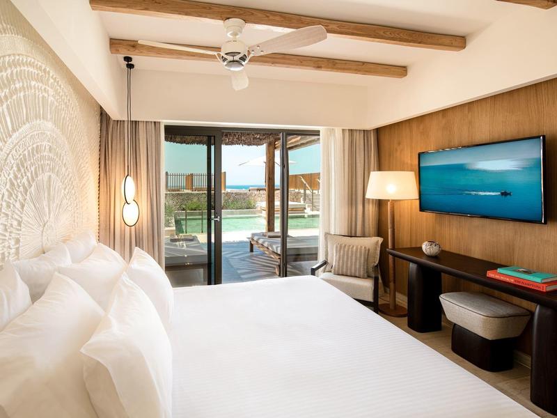 Camera d'hotel moderna con letto matrimoniale, dettagli in legno e balcone con vista sull'acqua