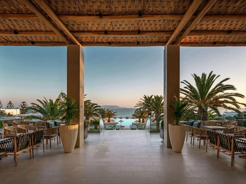 Sala da pranzo aperta con vista sulla piscina e sul mare al tramonto.