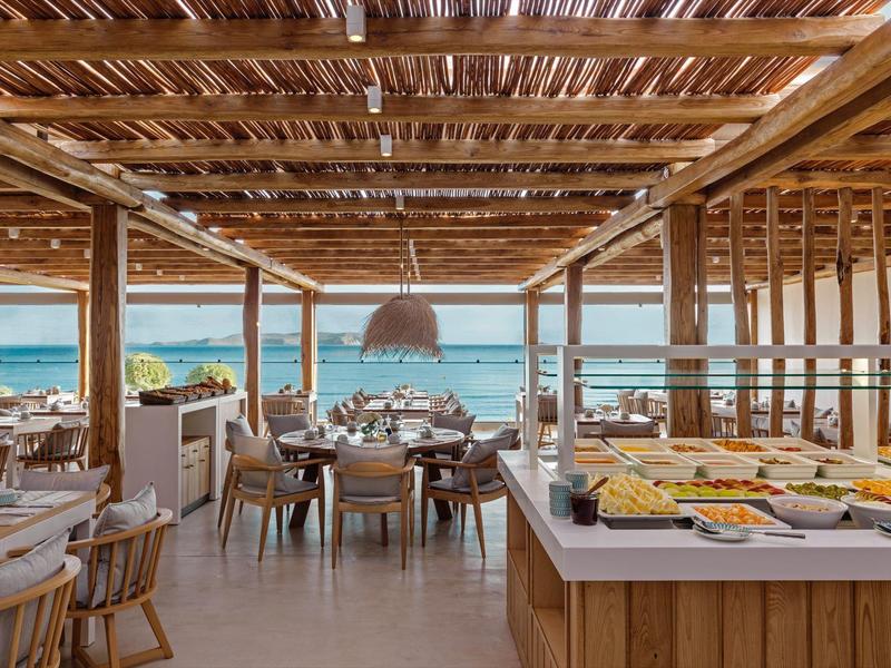 Ristorante aperto in legno con vista mare e tavoli apparecchiati in un hotel.