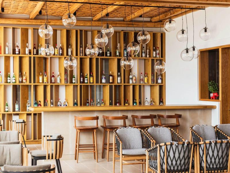 Bar di hotel moderno con scaffali in legno, sedie e divani in un'atmosfera calda e accogliente.