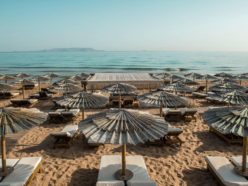 Spiaggia con più ombrelloni e lettini vicino al mare con tempo sereno.