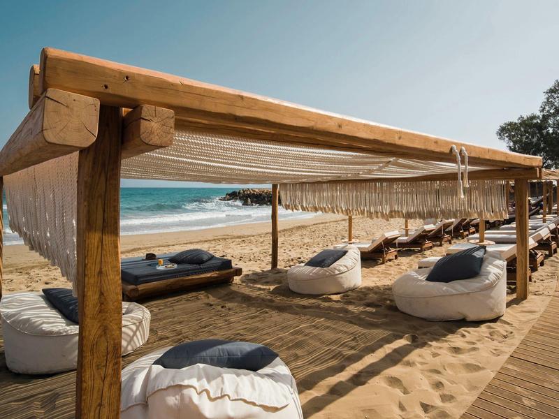 Spiaggia con sedie a sdraio e comodi pouf sotto una copertura in legno