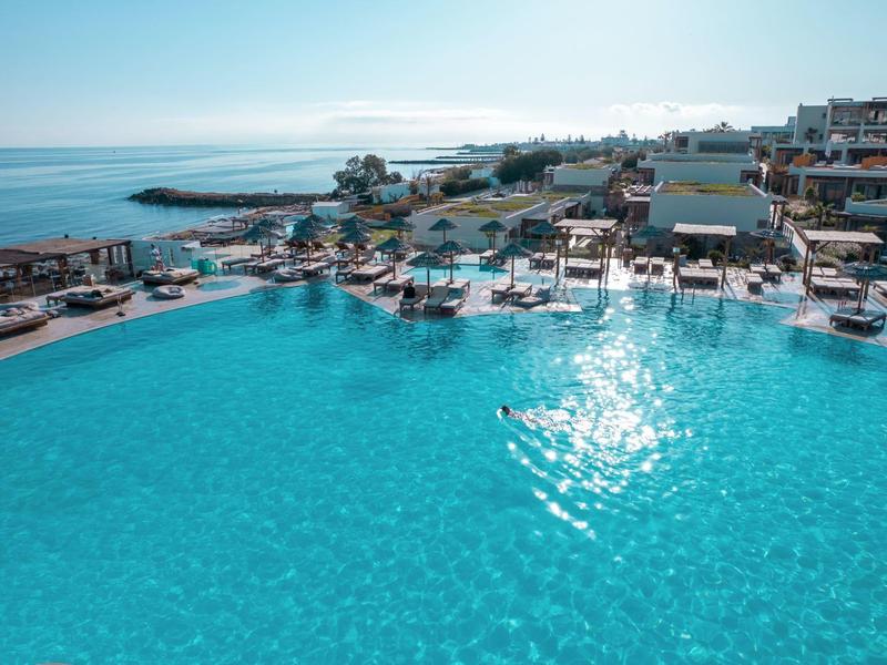 Grande piscina con vista sul mare e lettini intorno.