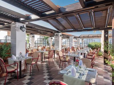 Outdoor-Restaurant mit gedeckten Tischen, Stühlen und Holz-Dach im Hotelgarten.