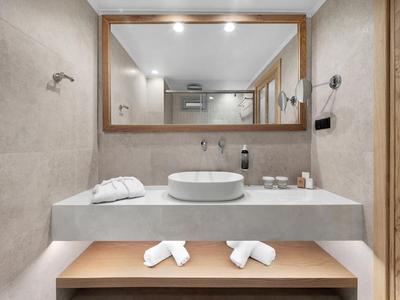 Modernes Hotelbadezimmer mit großem Spiegel, rundem Waschbecken und weißen Handtüchern.