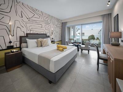 Modern eingerichtetes Hotelzimmer mit großem Bett, Balkon und Meerblick.