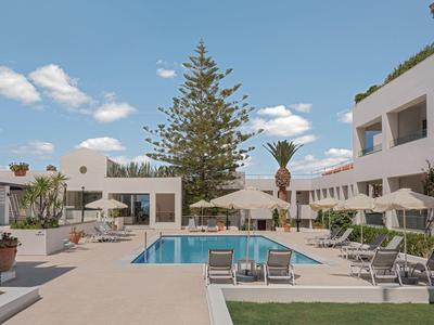 Piscina moderna dell'hotel con sedie a sdraio e ombrelloni sotto un cielo azzurro.