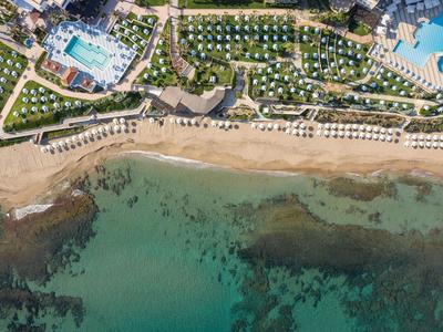 Pláž s deštníky, lehátky a bazény u hotelu u moře.