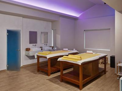Modernes Massagezimmer mit zwei Holzmassagebetten und entspannender violetter Lichtdecke.