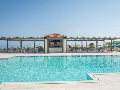 Moderner Poolbereich mit klarem Wasser und überdachter Lounge in sonnigem Hotelumfeld.