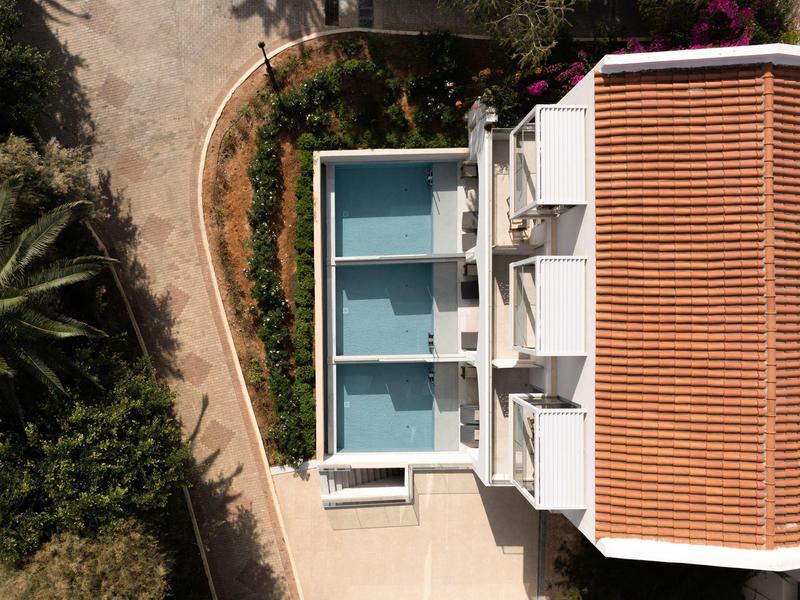 Letecký pohled na obdélníkový bazén vedle budovy s taškovou střechou.