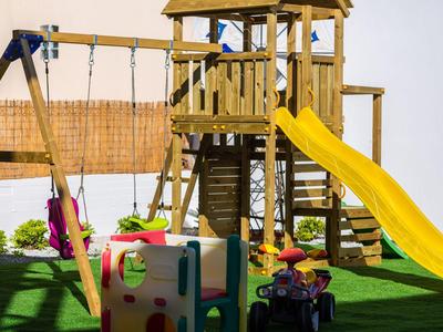 Children's playground with climbing frame, slide, and swings on green grass