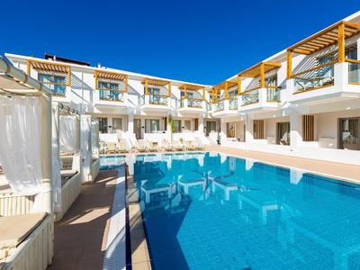 Moderner Hotelkomplex mit großem, blauem Pool, weißen Gebäuden und klarem Himmel.