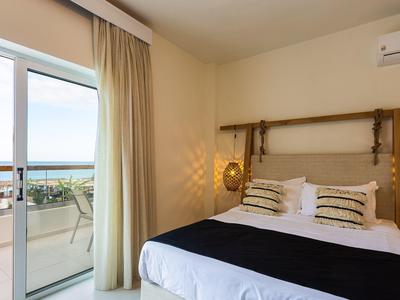 Gemütliches Schlafzimmer mit Doppelbett, Meerblick vom Balkon und warmer Beleuchtung.