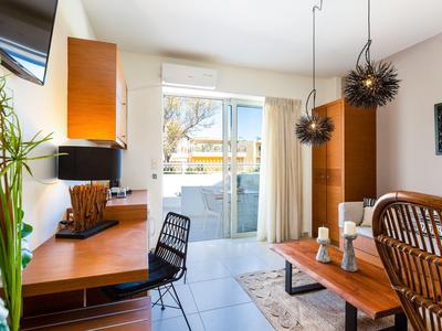 Helles Wohnzimmer mit Holzmöbeln, schwarzem Stuhl, Pflanzen und Glas-Schiebetür zum Balkon.