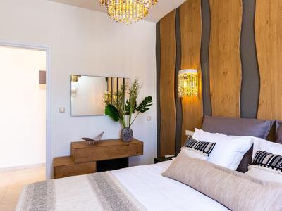Modernes Schlafzimmer mit Holzwand, Hängelampe, gemütlichem Bett und Dekoration auf Kommode.