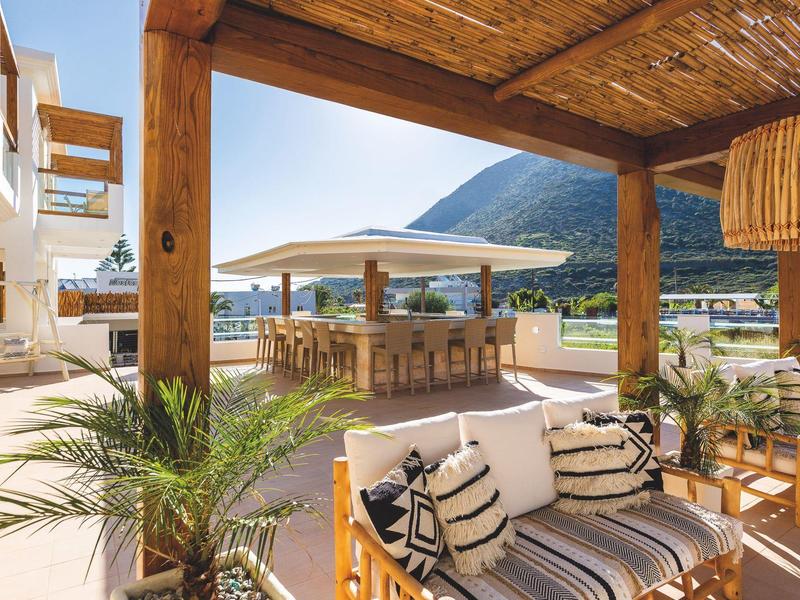 Cozy outdoor seating with wooden furniture and views of mountains and terrace umbrellas.