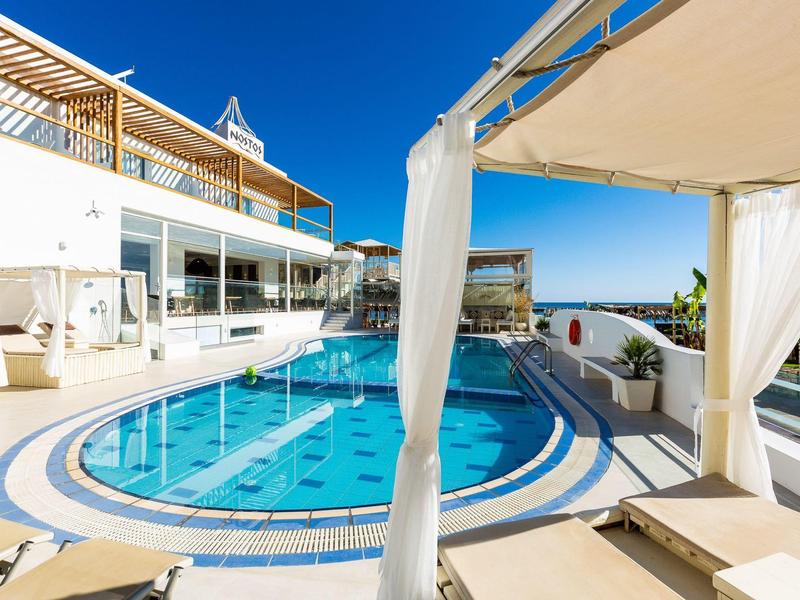 Modern outdoor pool with loungers and sunshade at a hotel in sunny weather.