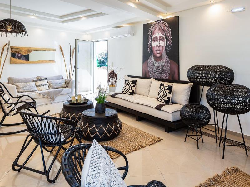 Bright living room with modern rattan furniture set, rugs, and large wall portrait.
