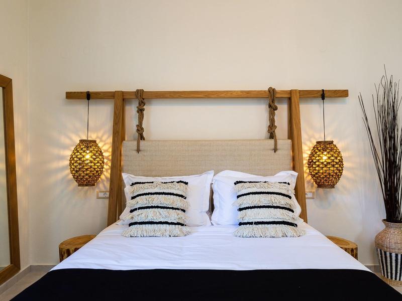 Modern bedroom with double bed, decorative pillows, and hanging wicker lamps.