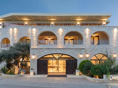 Hotel elegante de varios pisos con fachada de piedra, grandes arcos y luces exteriores cálidas al anochecer.