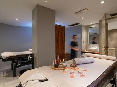 Sala de spa tranquila con camilla de masaje, luz cálida y elementos decorativos para relajación en hotel.