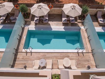 Tre piscine adiacenti con ombrelloni e lettini ai bordi.