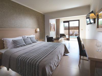 Habitación de hotel luminosa con cama grande, escritorio, silla y terraza con vista al mar.