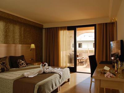 Habitación de hotel acogedora con balcón, cama doble, televisor y mesa con silla.
