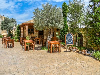 Accogliente terrazza con tavoli e sedie in legno accanto a un piccolo bar in stile mediterraneo.